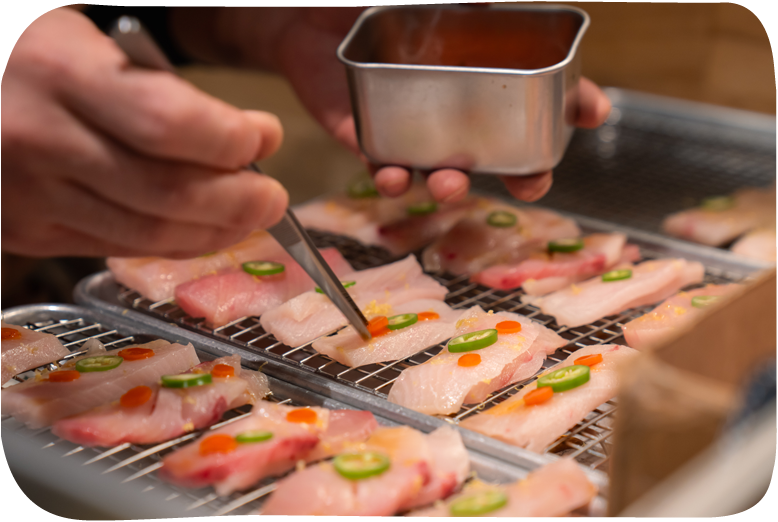 Chef preparing sushi with sliced jalapeños and roe